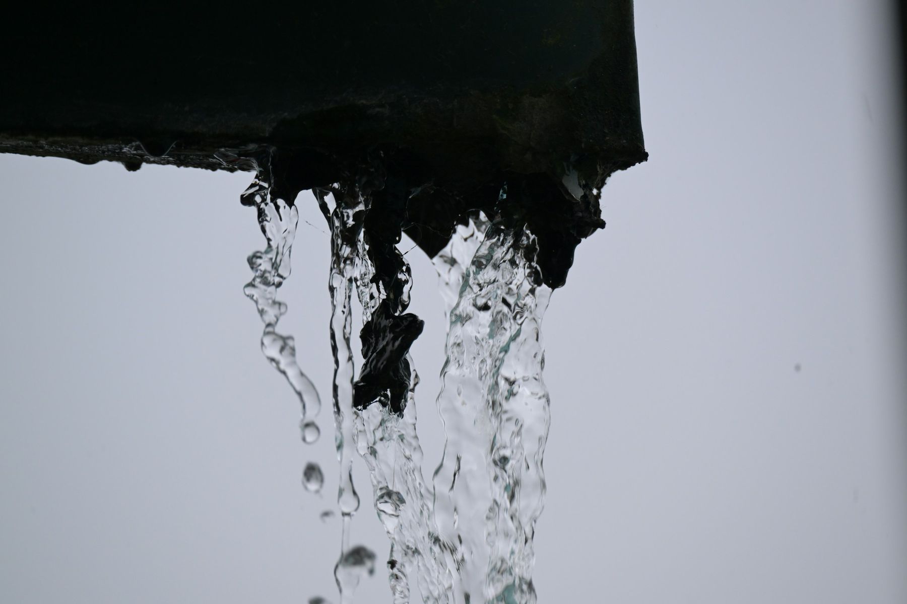 Rainwater pouring off the end of a gutter