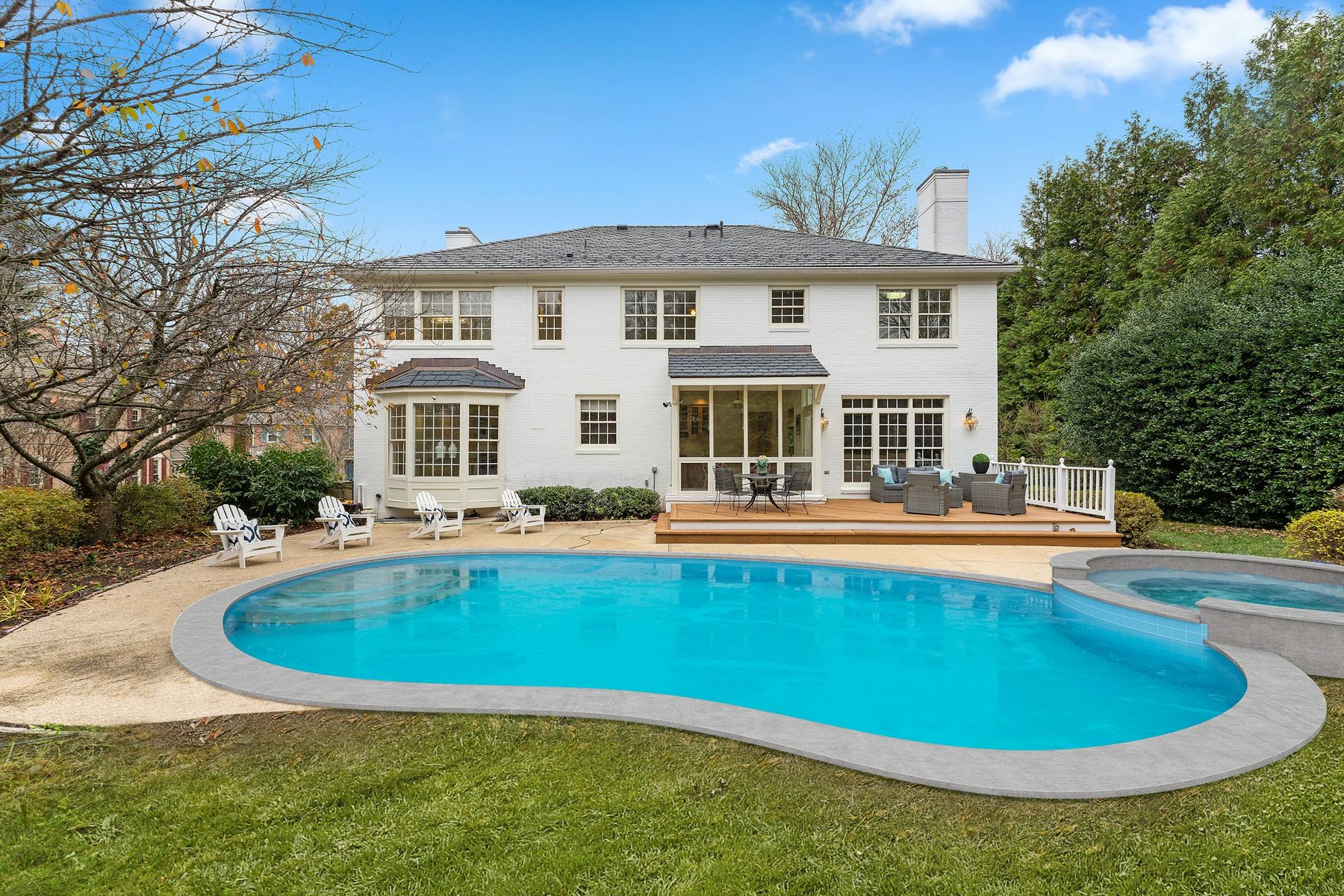 Una piscina con terraza junto a una casa blanca